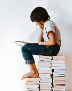 child reading while sitting on stacks of books