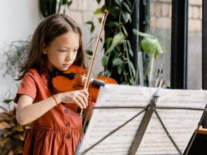 young female student playing violin with music stand in front of her