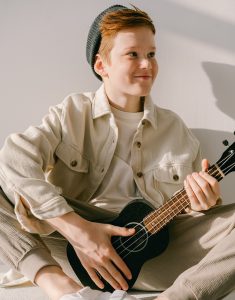 middle school male student holding ukulele