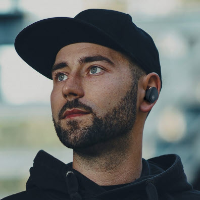 Man with cap in profile with earbud in left ear.