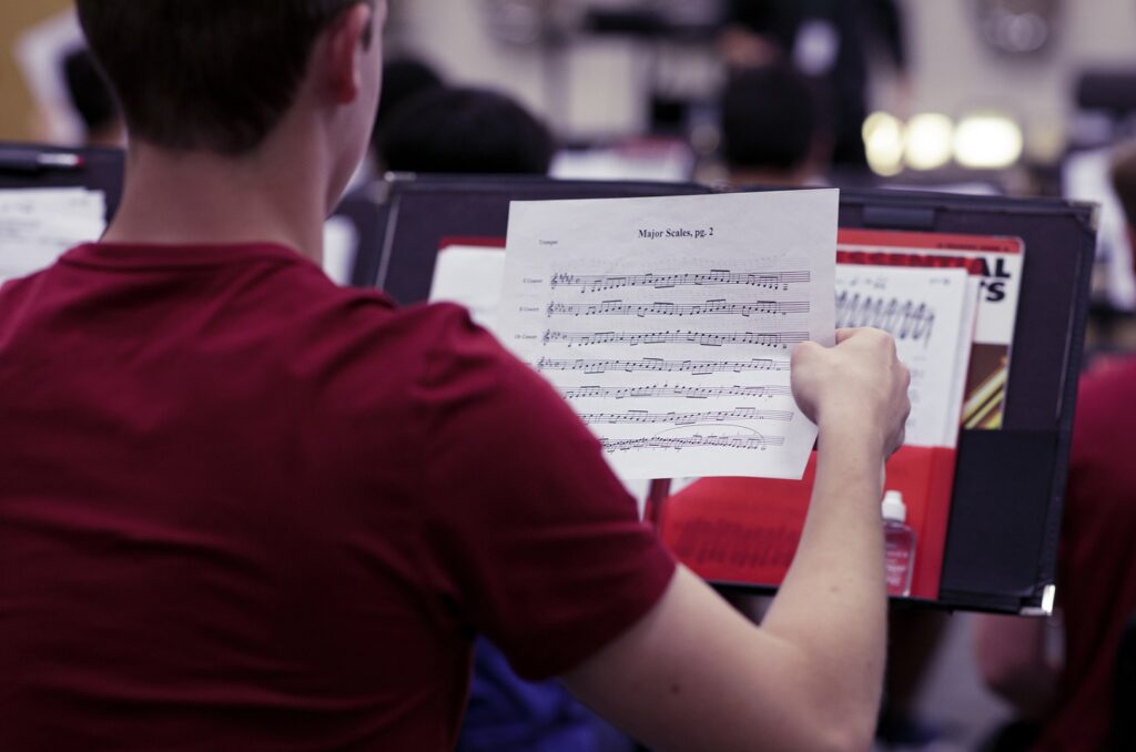 student putting sheet music into folder on music stand