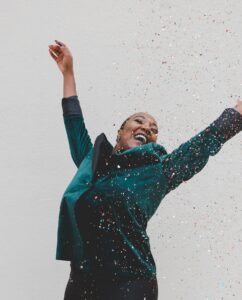 woman jumping up for joy with confetti around her