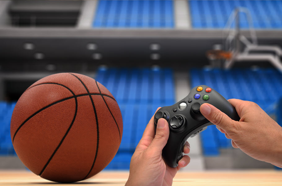Hands holding a gaming control with a basketball and empty arena in background.