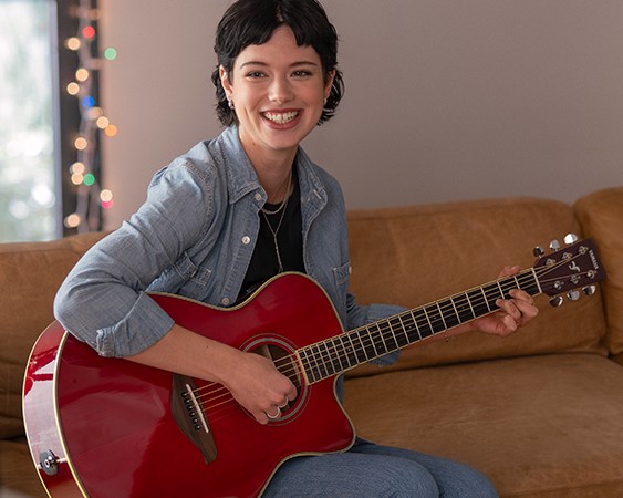 Woman playing a red acoustic guitar.