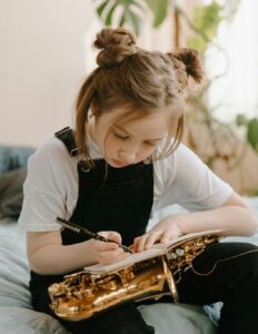 student composing in notebook while holding saxophone