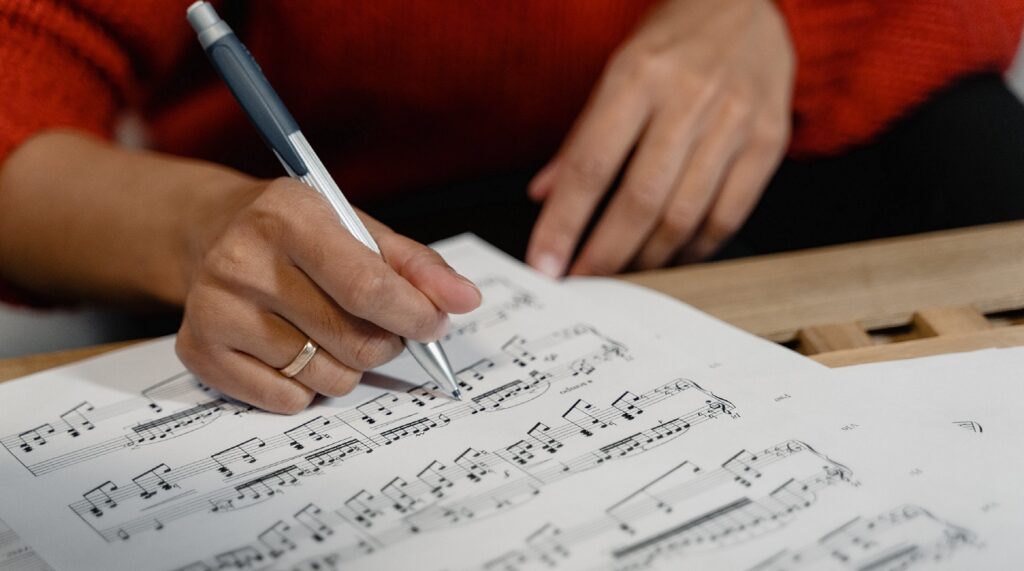 close up of someone holding pen over sheet music