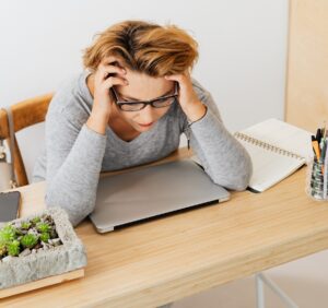 woman sitting at desk with head in her hands