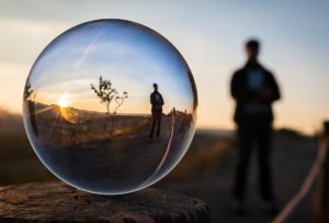 photo art of large bubble that reflects the scene of a person standing in field