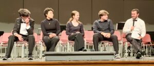 four students and music teacher on stage