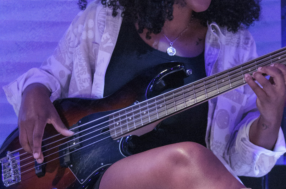 Closeup of a woman playing a bass guitar.