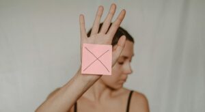 woman holding up hand with a sticky note with an X on it