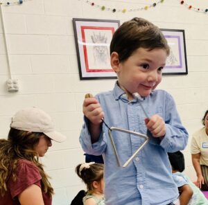 young student holding triangle in music class