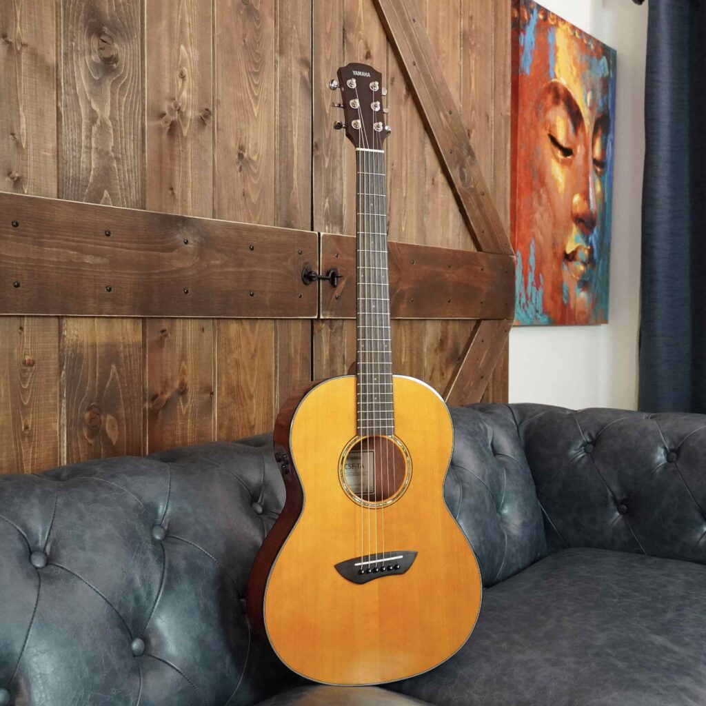 An acoustic guitar on a sofa.