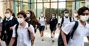 students wearing masks while walking in school hallway 