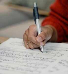 hand holding pen and writing on score