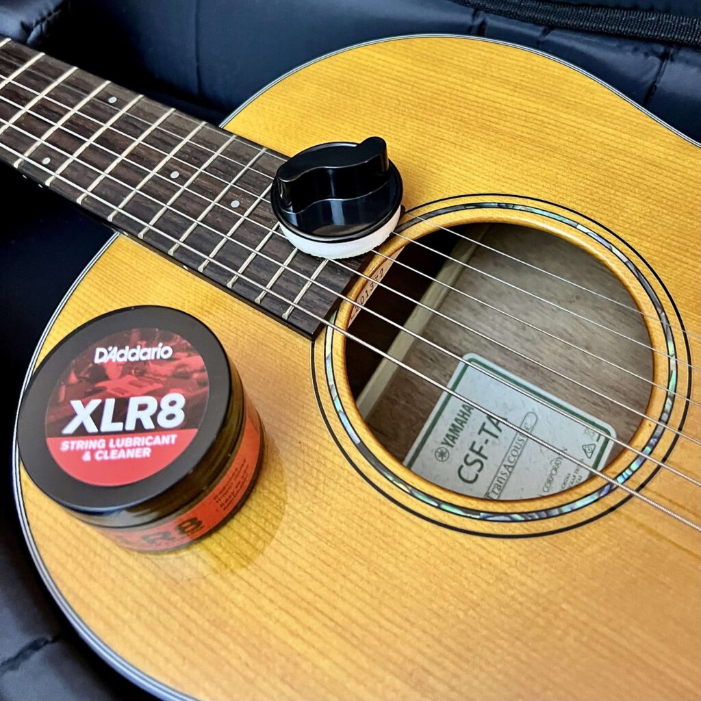 A can of string lubricant and cleaner on top of an acoustic guitar.