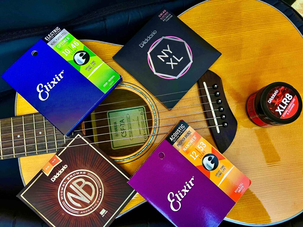 Several sets of guitar strings on top of an acoustic guitar.