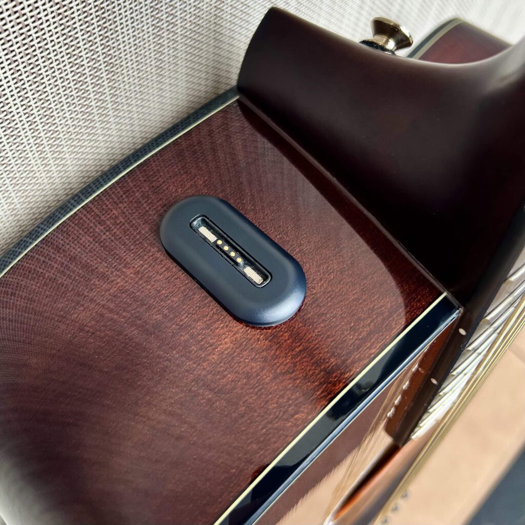 A magnetic charger on the top of an acoustic guitar.