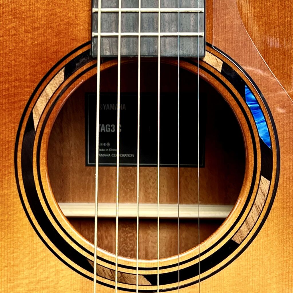 An acoustic guitar sound hole surrounded by a multi-color wood inlay.