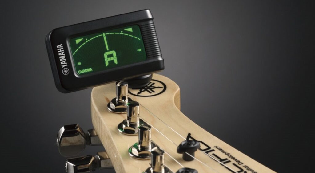 A clip-on tuner attached to an electric guitar headstock.