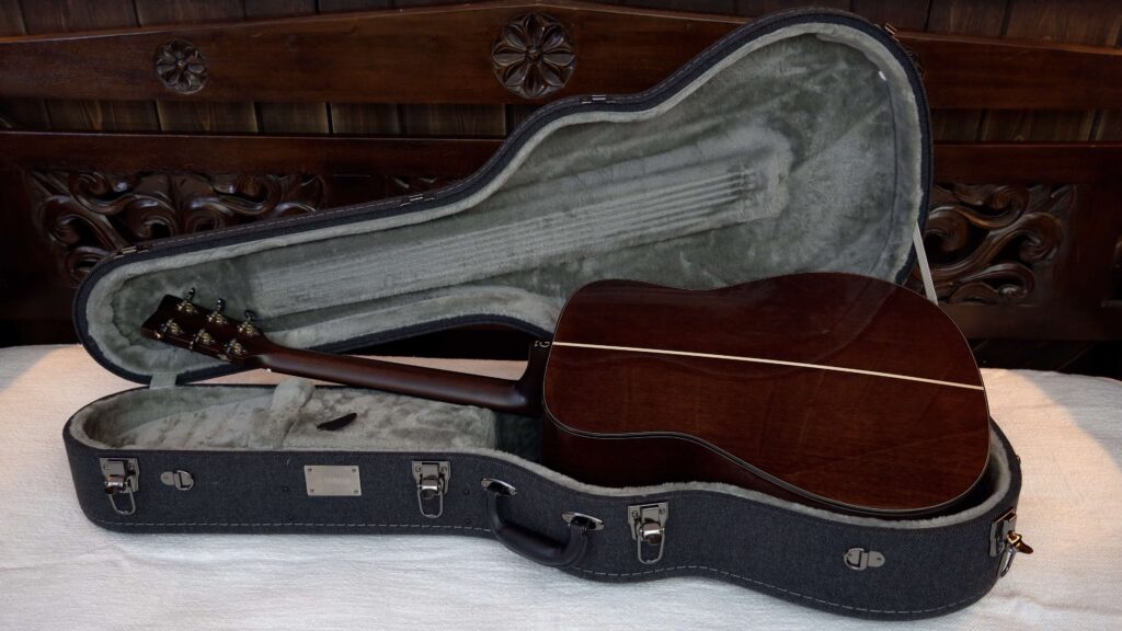 An acoustic guitar in a hardshell tweed case.