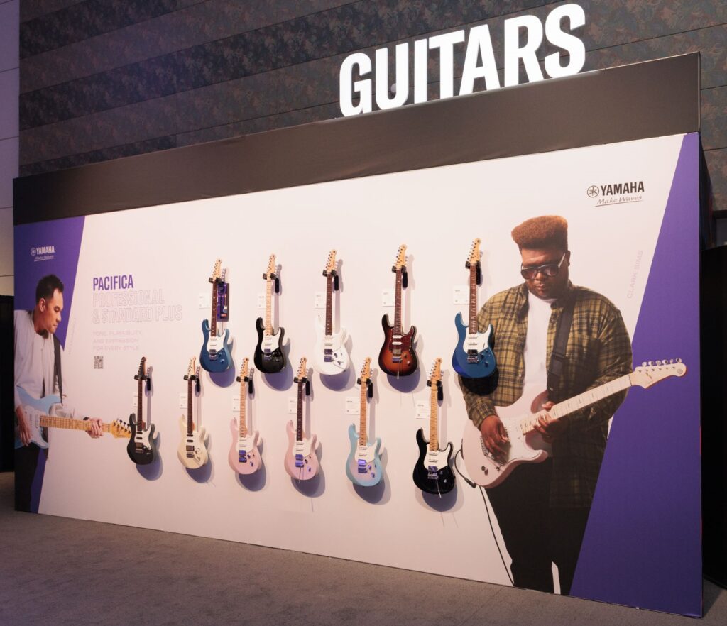 Eleven electric guitars hanging on a wall display at 2025 NAMM.