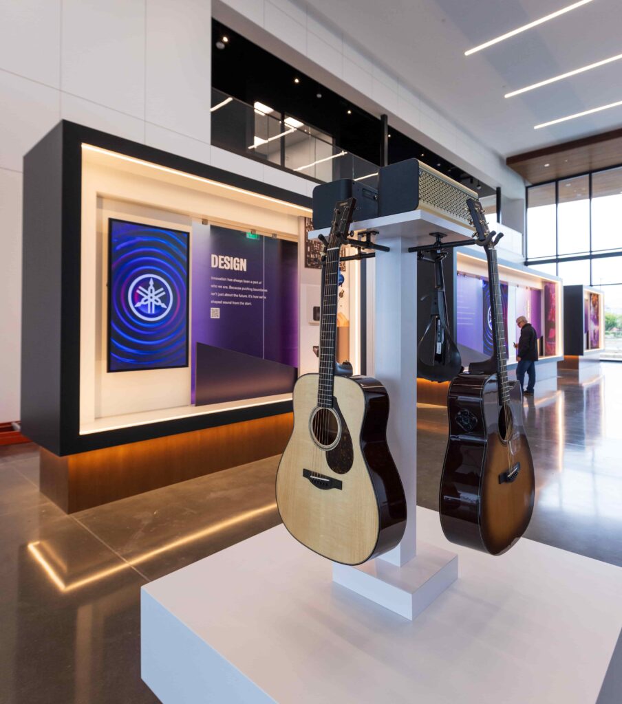 Two guitars hanging on a display in the lobby of an office building.