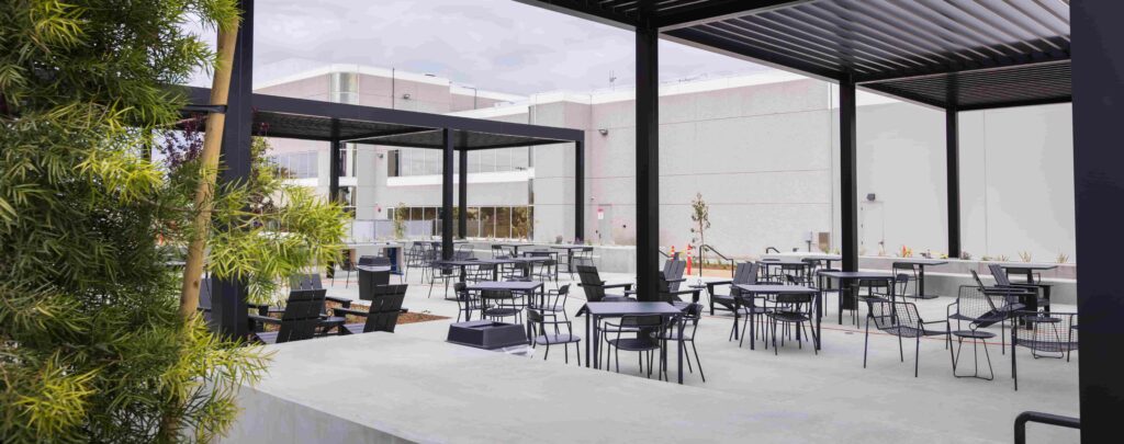 A group of tables and chairs on a patio outside an office building.