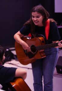 guitar teacher playing in front of student