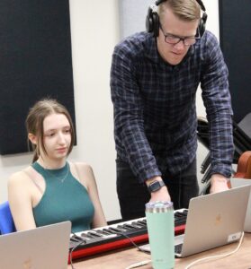 music educator with a female student sitting at a DAW