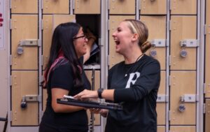 two flute students laughing while standing in front of lockers