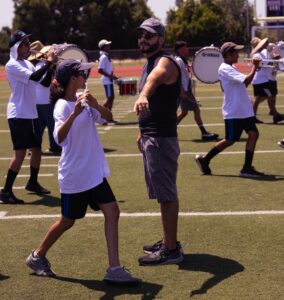 music educator rehearsing outdoors with marching band