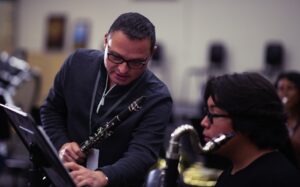 music educator holding clarinet and helping student