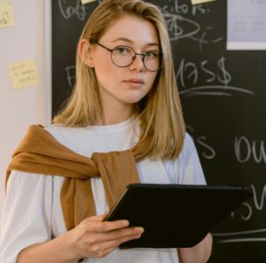 young female holding tablet and standing in front of chalkboard