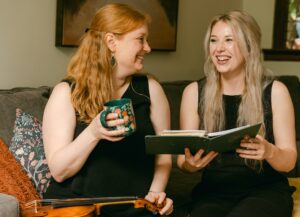 Alexandra Blaine and Annie Ray sitting side by side on couch