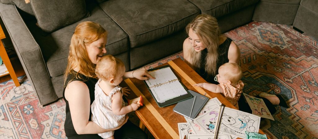 Alexandra Blaine and Annie Ray sitting around coffee table with their daughters