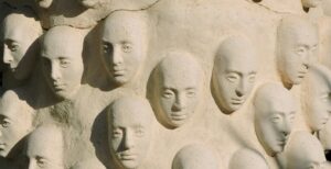 sculpture of cloned faces on a wall