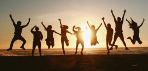 silhouette of a group jumping in excitement as the sun sets