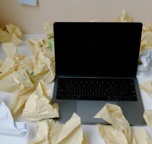 laptop surrounded by crumpled papers