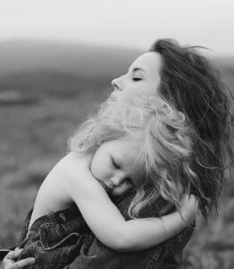 woman holding a child while standing outdoors