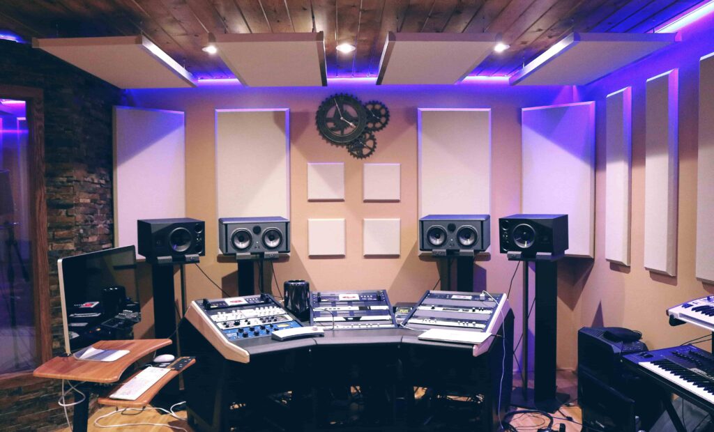 A home studio with a small mixer and four speakers. The picture shows extensive acoustic treatment on the ceiling and on the walls, with both diffusers and absorbers, plus bass traps in the corners.