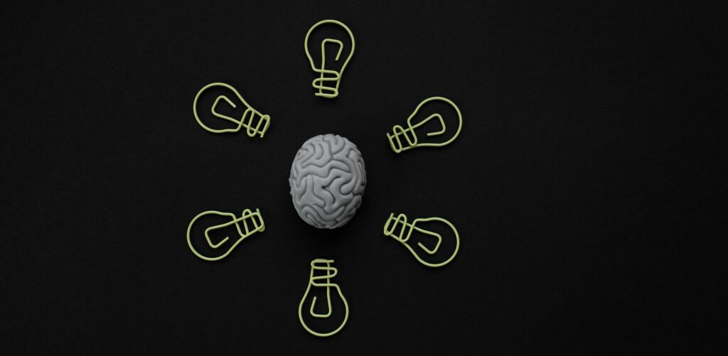 artwork of brain surrounded by six lightbulbs