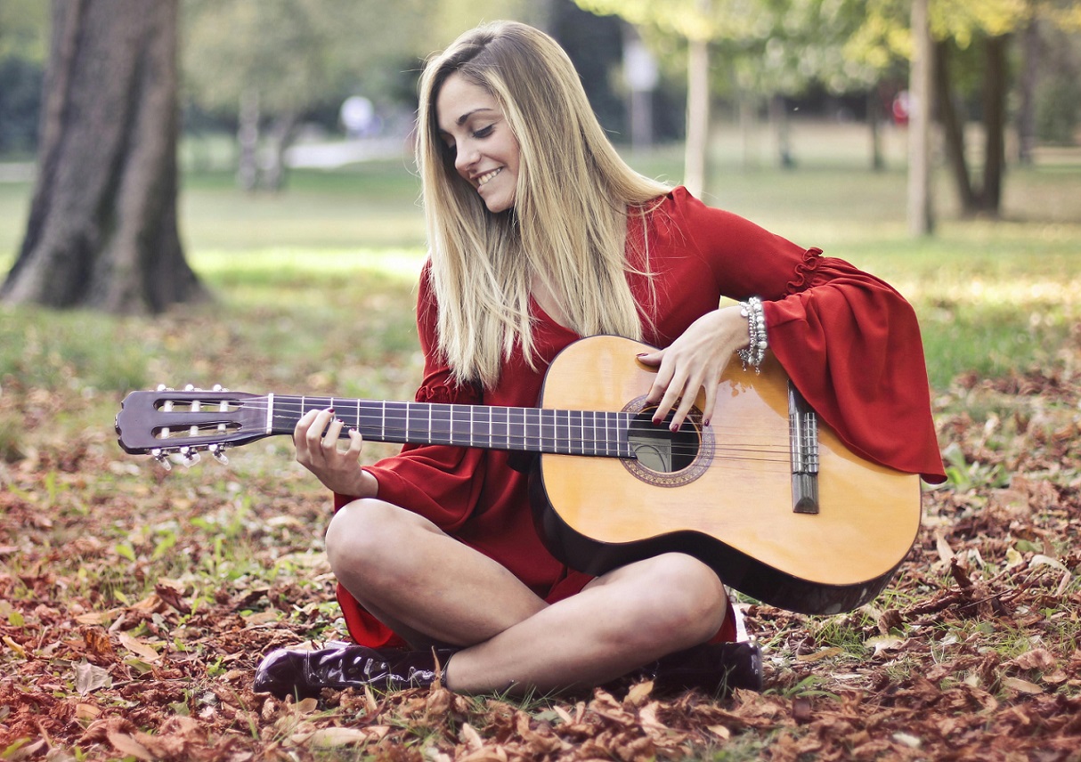 female playing guitar outdoors