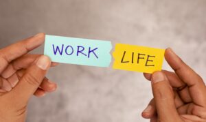 hands holding up two pieces of paper that say "work" and "life"