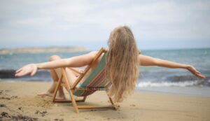 woman sitting in a beach chair with arms outstretched