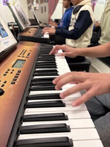 close up of hands playing piano in group piano class