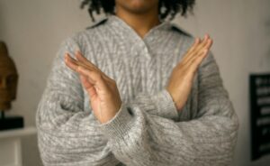 person with hands in front of her torso in an X 