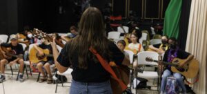 guitar instructor in front of class with students seated in front of her