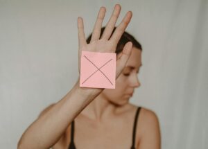 woman holding up hand with a stick note with a big X on it