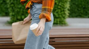 someone walking holding sack lunch and coffee cup